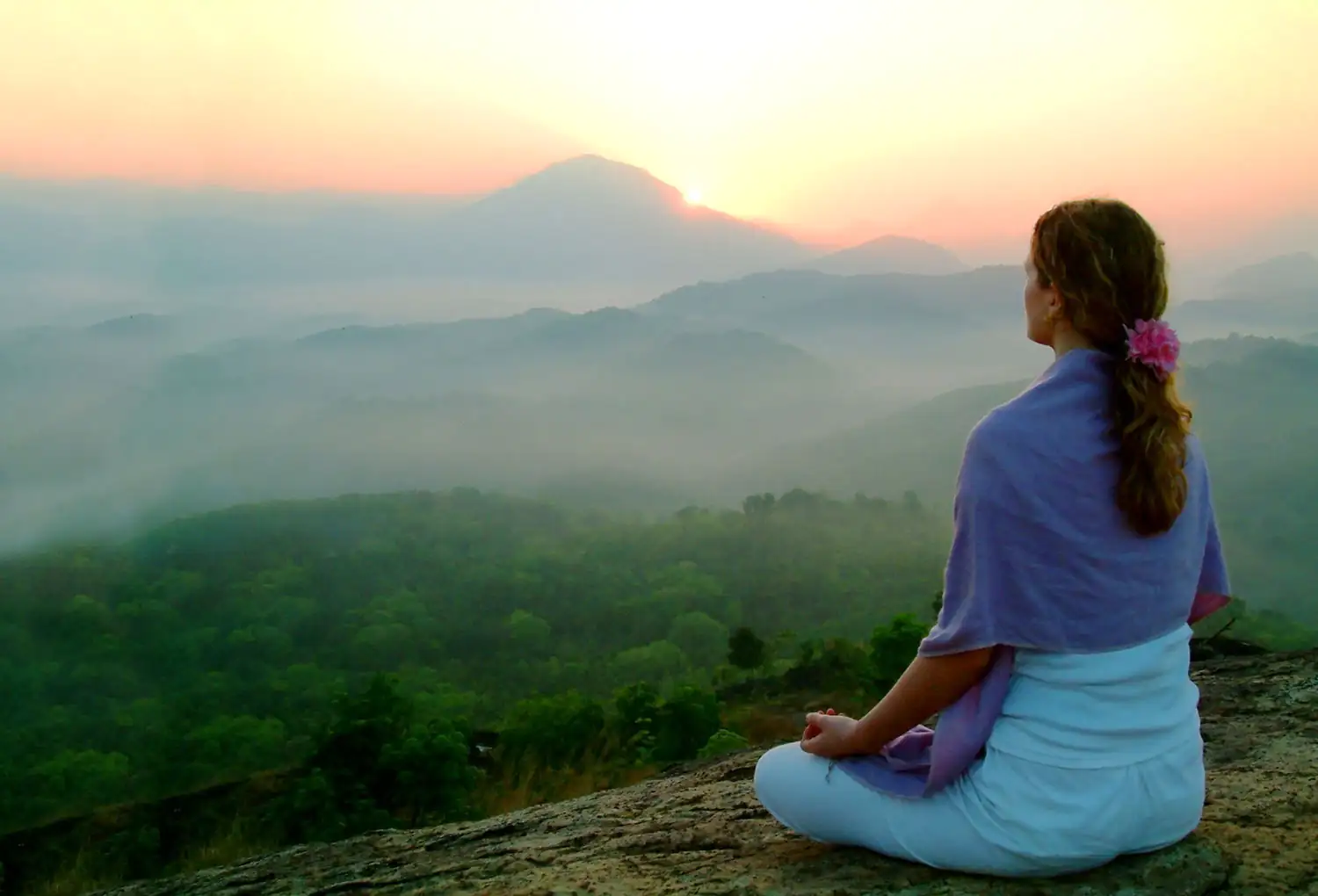 Woman meditating in nature with the rising sun